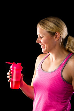 Happy woman holding pink bottle with energy drink