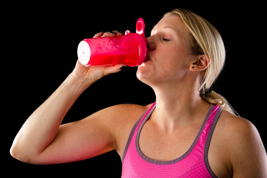 Woman drinking energy drink from pink bottle