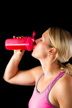 Woman drinking energy drink from pink bottle