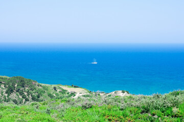 Beautiful seascape with calm blue Mediterranian sea, mountains in mist and boat, touristic season, vacation on sunny islands