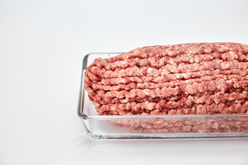 Fresh minced meat close-up in a glass dish plate. Isolated on a white background.