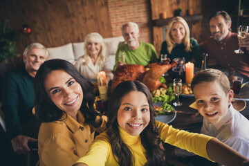 Self-portrait of nice attractive cheerful big full family brother sister gathering having fun eating festal domestic meal autumn harvest celebration custom at modern loft brick industrial interior