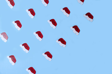New Year's patern, little hats of Santa Claus lie rhythmically on a blue background