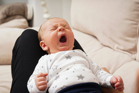 Bebe bostezando en las piernas de su madre