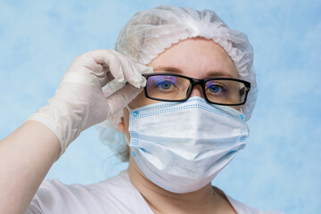 
A nurse of European appearance in white overalls on a blue background. Close-up. Place for an inscription.