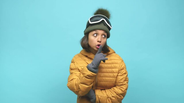 Young snowboard indian woman keeping a secret or asking for silence