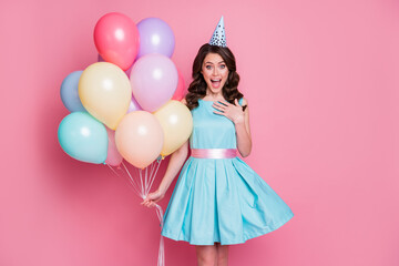 Obraz na płótnie Canvas Photo of charming shocked lady festive event birthday party carry many balloons surprise holiday overjoyed wear blue teal short dress cone cap isolated pastel pink color background