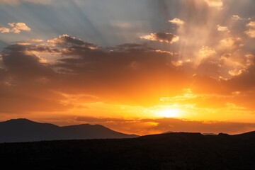 Beautiful bright sunset sky over the mountains silhouette . Dramatic orange clouds after sunset. Nature backgrounds. Golden sunset.