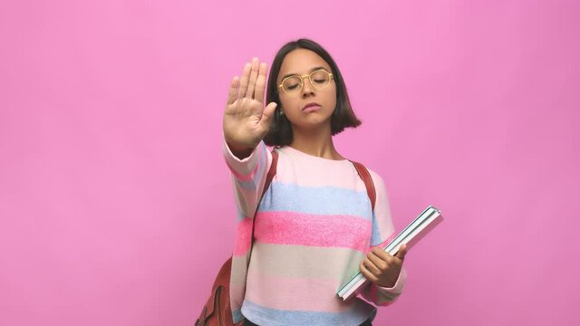 Young student indian woman standing with outstretched hand showing stop sign, preventing you