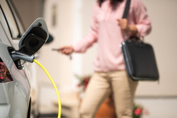 Close up of a electric car charger with female silhouette in the background