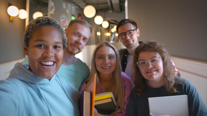 Group of university friends taking self-portrait standing in corridor