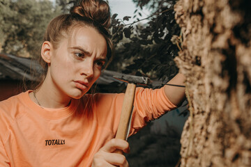 
Attractive girl hammers a nail with a hammer