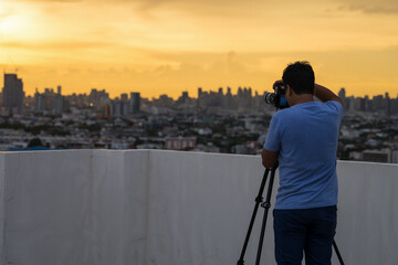young man with professional camera photographing the city from the top