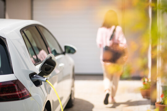 Close up of a electric car charger with female silhouette in the background