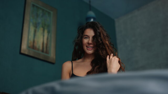 Sexy girl biting lip in modern bedroom. Long hair woman posing in bed.