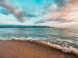 Ocean sunset, waves washing in over the sand. Strong sunset colors and clouds over the horizon