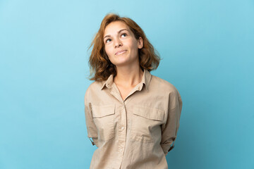 Young Georgian woman isolated on blue background and looking up