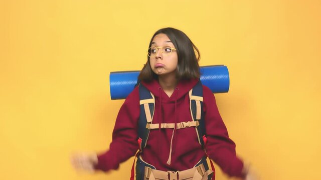 Young hiker indian woman shrugs shoulders and open eyes confused