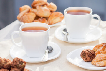 Fresh homemade sugar cookies with tea on white table with sun lights. Good morning or day concept.