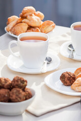 Fresh homemade sugar cookies with tea on white table with sun lights. Good morning or day concept.