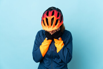 Young cyclist woman isolated on blue background with tired and sick expression