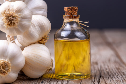 Glass bottle of garlic oil and Ripe and fresh garlic plant on wooden or rustic table, alternative medicine, organic cleaner.