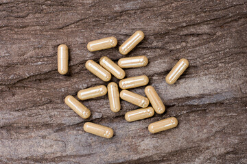 Green natural herbal medicine capsule pill isolated on wood table background. Alternative supplement concept.