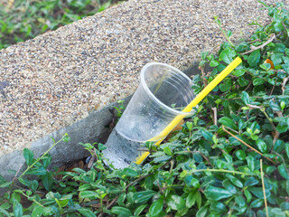 Plastic waste glass tube transparent yellow Was left on the edge of a bush in a park