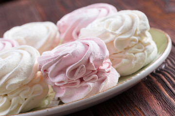 Pink and white meringue cookies on green plate