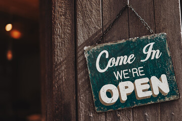 Open sign broad hanging on wood door front of cafe.