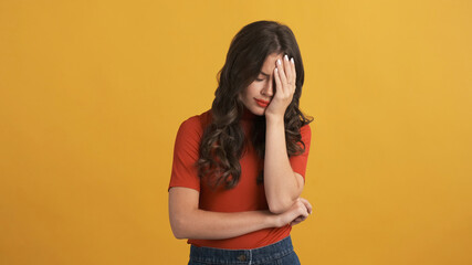 Sad girl covering face with hand over colorful background. Face palm expression