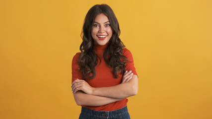 Beautiful excited girl in red top with hands crossed happily looking in camera over colorful background