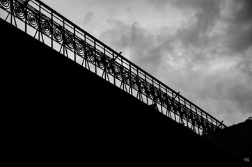 
black and white railing on the roof of a building with huge clouds