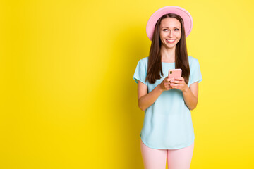 Photo positive cheerful girl blogger use smartphone look copyspace enjoy social network post comment news wear pink trendy pants trousers sunhat isolated bright shine color background