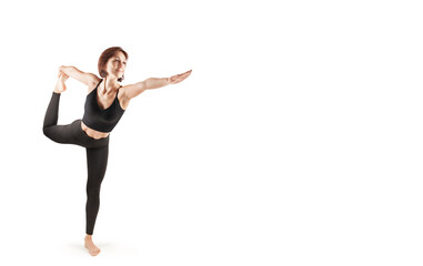 young beautiful woman in black leggings and top doing fitness indoors, on a white background, isolate