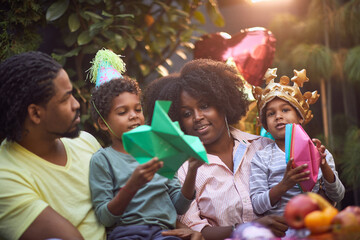 Fototapeta premium afro-american family gathered on birthday party playing with paper hat and boats