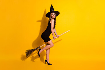 Fototapeta na wymiar Full length body size profile side view of her she nice attractive thin funny amazed lady wizard riding broom having fun pout lips isolated bright vivid shine vibrant yellow color background