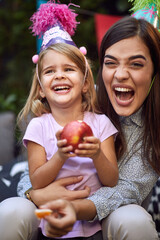  beautiful young brunette laughing with cute little girl in her lap