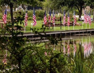 American Flags reflecting off the water of a pond in a public park in Montgomery, TX.
