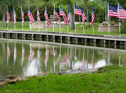 American Flags reflecting off the water of a pond in a public park in Montgomery, TX.