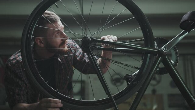 The cyclist repairs the bike in a garage, turns the wheel