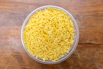 Yellow Rice in a Circular Container on a Wood Table