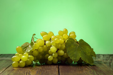 Ripe green grape and on wooden table over green background.