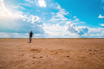 A woman on a Bicycle rides on the sand on a Sunny day, leaving footprints in the sand