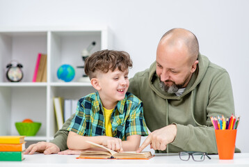 Father and his happy young son doing homework together at home