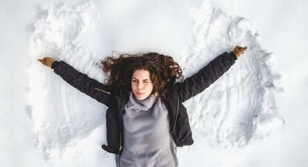 Fototapeta na wymiar Portrait of beautiful woman on snow making angels wings.