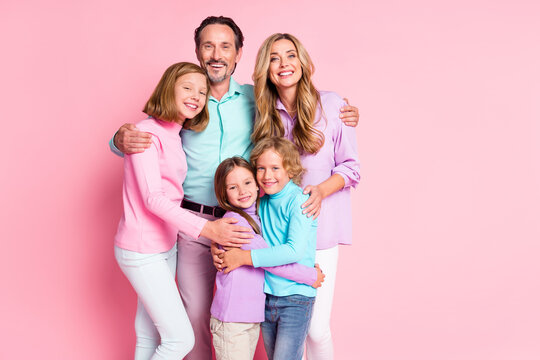 Photo of positive mommy daddy and three preteen kids children enjoy togetherness hug cuddle embrace wear casual style clothes isolated over pastel color background