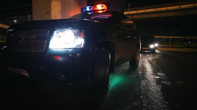 police cars in high speed pursuit. Emergency response police patrol vehicle speeding to scene of crime at night and rain. Outdoor front view of police traffic auto driving.