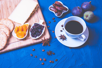a cup of kofu, cheese, dried fruit, crackers and fresh figs
