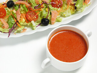 Tomato soup and fresh salad on a white plate
